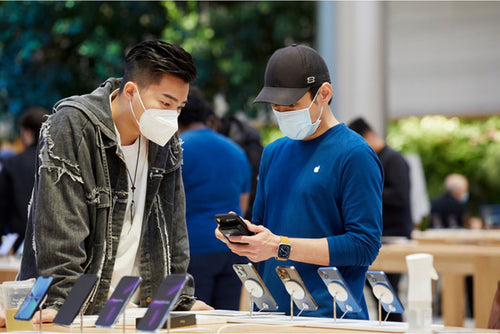 Un hombre y un vendedor examinando el iPhone 13